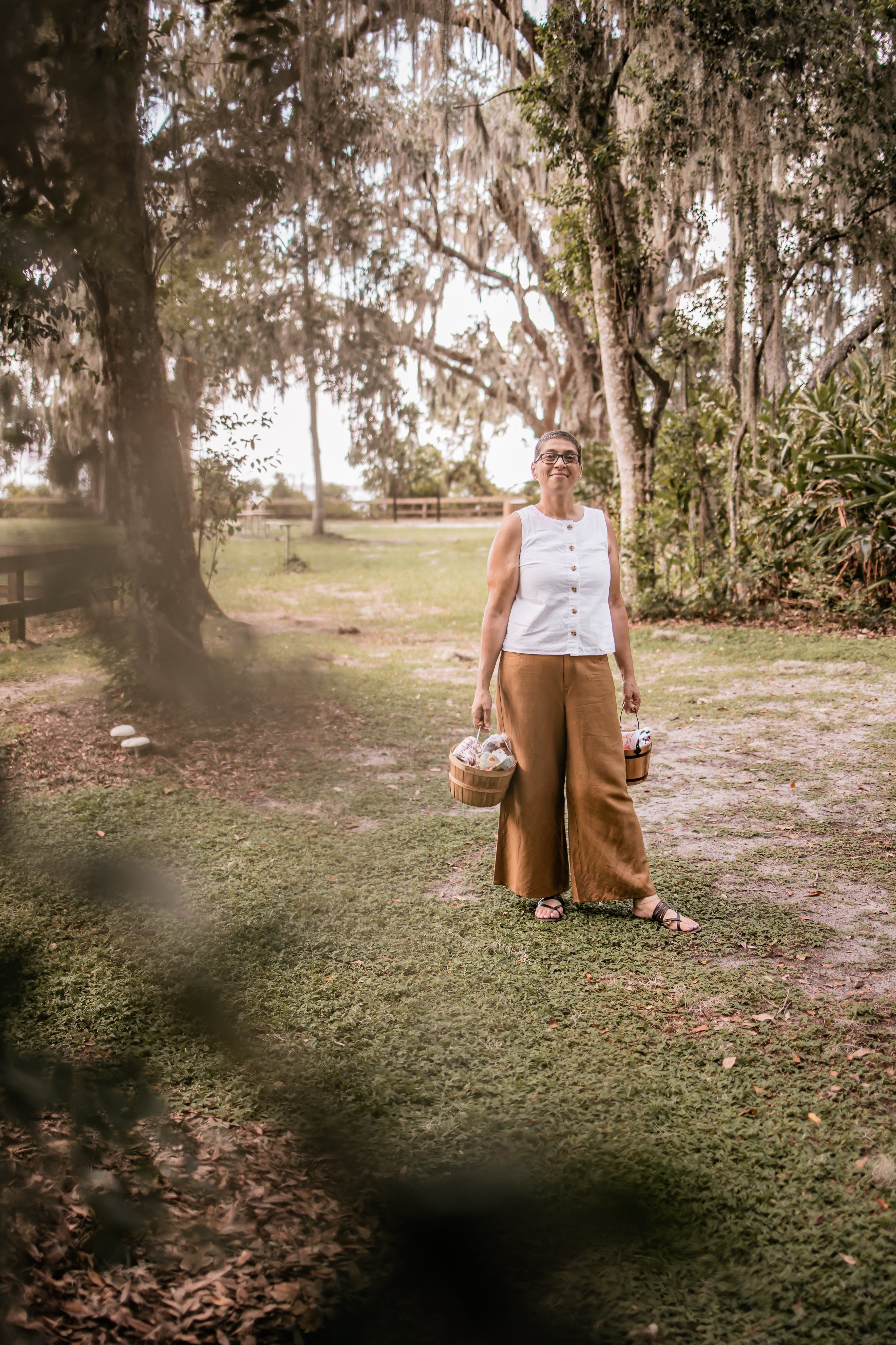Person standing in a park-like setting with trees and grass.
