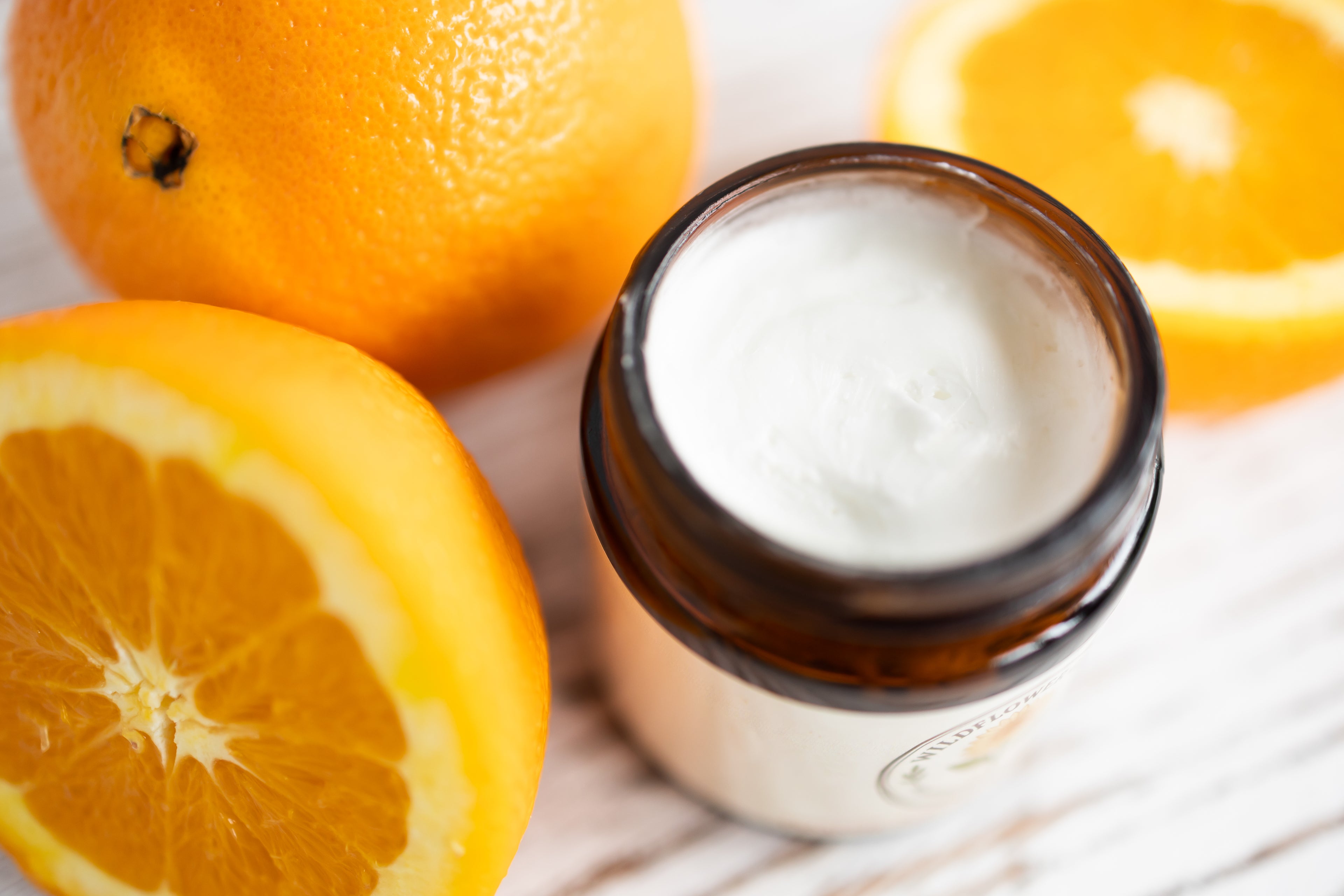 Jar of cream with oranges on a wooden surface