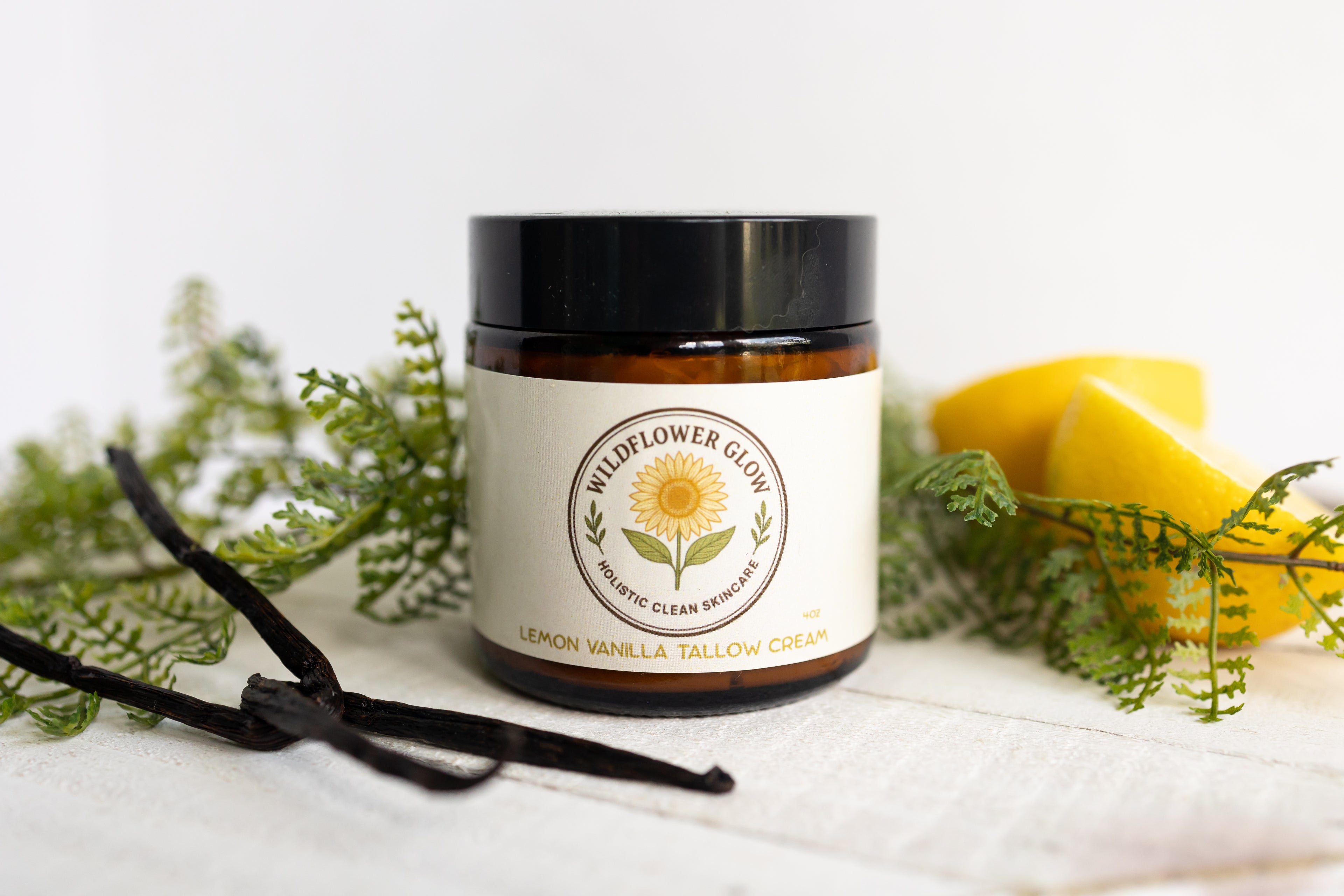 Jar of Wildflower Glow product with vanilla bean and lemon on a white background