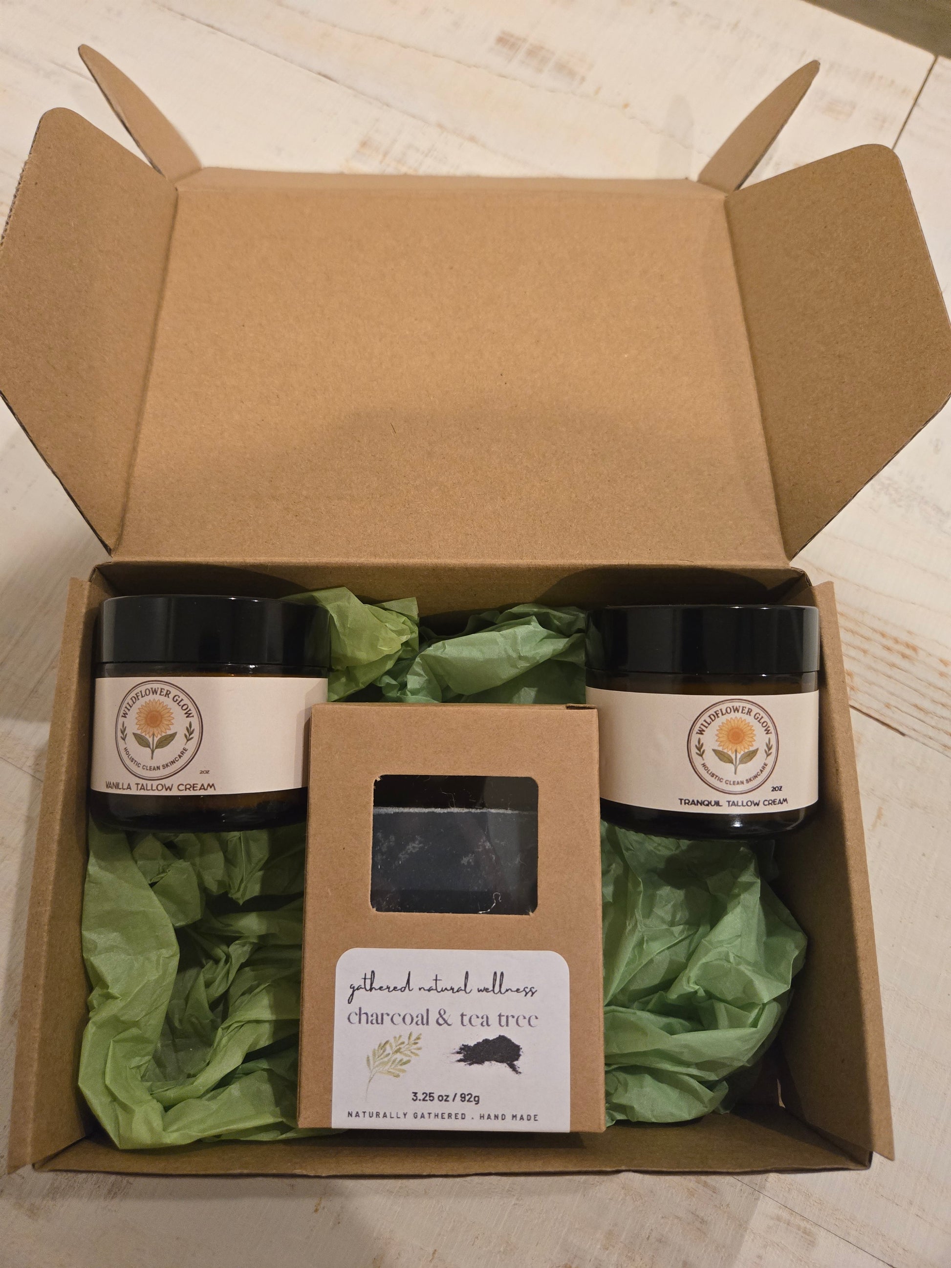 Open box with moisturizing tallow cream, magnesium tallow cream and packaged charcoal and tea tree soap bar.  